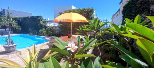 a person sitting under an umbrella next to a pool at The Sandcastle Guesthouse - Melkbosstrand in Melkbosstrand