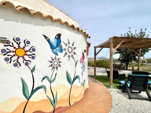 een muur met een muurschildering van bloemen en een vlinder bij Cave Houses Ed Yara and Nadieh with PRM facilities in Margen de Abajo