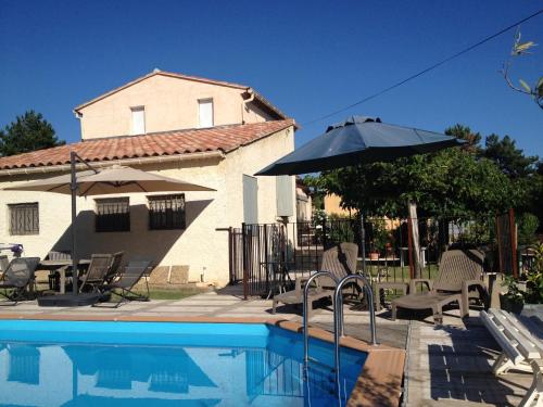 une piscine avec des chaises et un parasol ainsi qu'une maison dans l'établissement Maison indépendante au pied du Ventoux, à Bédoin