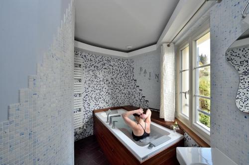 a woman laying in a bath tub in a bathroom at Chambres d'hôtes Villa de Vienne-en-Arthies in Vienne-en-Arthies