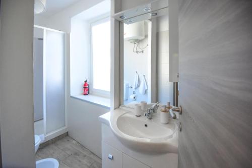 a white bathroom with a sink and a mirror at La Casa dei Laghi 1 Comabbio Monate Maggiore Orta in Mercallo