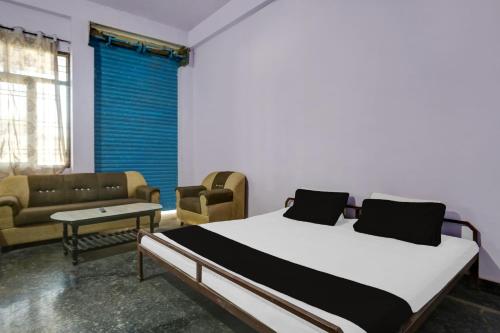 a bedroom with a bed and two chairs and a couch at OYO Flagship Aravali Guest House & Restaurant in Kishangarh