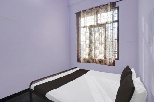 a white bedroom with a bed and a window at OYO Flagship Aravali Guest House & Restaurant in Kishangarh