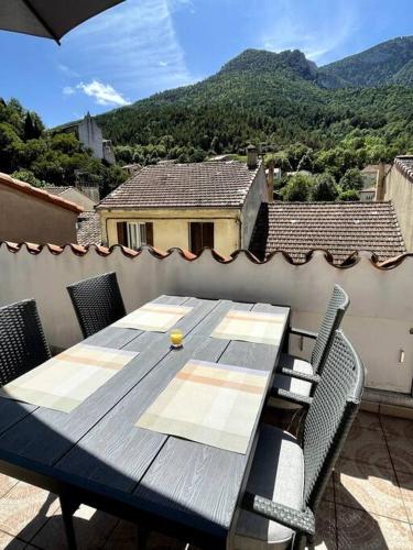 d'une table et de chaises en bois sur un balcon avec vue. dans l'établissement Townhouse in Southern France with a wonderful view, à Axat