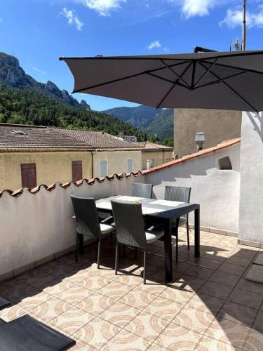 - une table, des chaises et un parasol sur la terrasse dans l'établissement Townhouse in Southern France with a wonderful view, à Axat