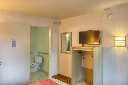 a bathroom with a toilet and a television on a wall at Motel 6-Everett, WA - North in Everett