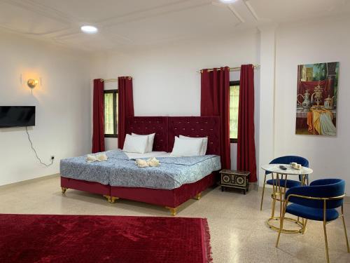 a bedroom with a bed with red curtains and a tv at Arabian Nights Nook in Muscat