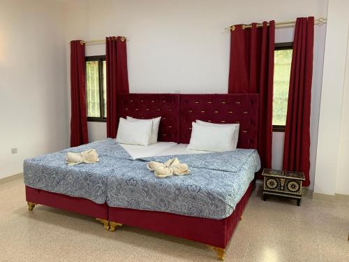 a bedroom with a bed with red curtains and two pairs of shoes at Arabian Nights Nook in Muscat