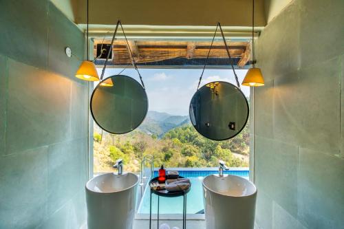 a bathroom with two sinks and a window with a view at StayVista at Leopard's Creek with Pool in Solan