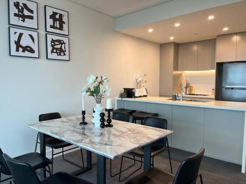 a dining room with a table with chairs and a kitchen at High-Rise with Park View in Sydney Olympic Park in Sydney