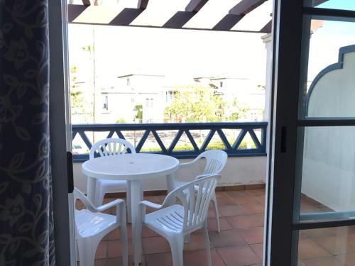 - Balcón con mesa blanca y sillas en Urbanización San Bruno by SIT ISLA CANELA, en Isla Canela