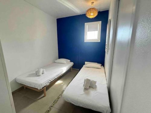 Cette chambre comprend 2 lits et un mur bleu. dans l'établissement Villa Pomelo - Jacuzzi - Piscine- Climatisation, à Lecci