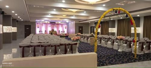 un salón de banquetes con filas de mesas y sillas en Marigold Celebration hotel, en Rāipur