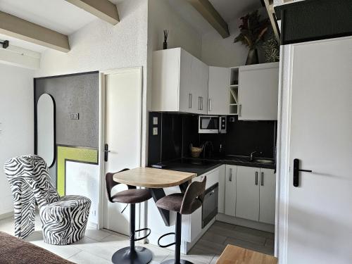 une cuisine avec des armoires blanches et une table et des chaises dans l'établissement Appartement Style Loft - proche Village Naturiste, au Cap d'Agde