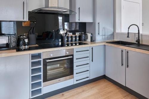 a kitchen with white cabinets and a sink and a stove at Host & Stay - Ropewalks Quarters in Liverpool