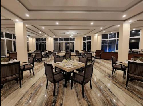 a dining room with tables and chairs and windows at Falettis Grand Hotel Murree in Murree