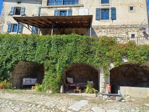 un bâtiment recouvert de lierre avec un banc et une table dans l'établissement Le château brangoly, à Enveitg