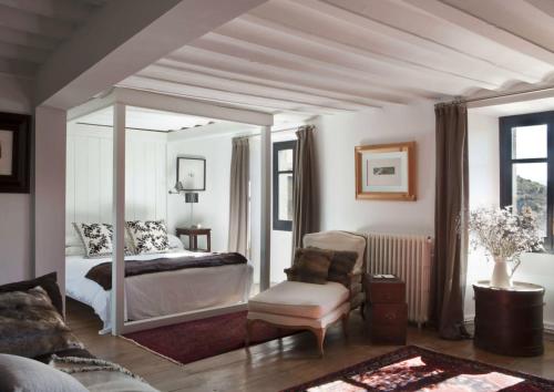 een slaapkamer met een hemelbed en een stoel bij Le château brangoly in Enveitg