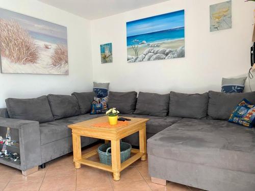 a living room with a gray couch and a table at Achtern Diek 12c - Wohnung 3 in Müggenburg