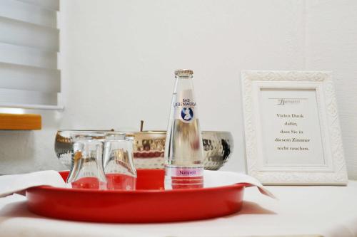 uma garrafa e dois copos numa bandeja sobre uma mesa em HERMANN Hotel Bar em Guben