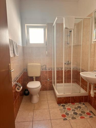uma casa de banho com um WC, um chuveiro e um lavatório. em Perica Apartments em Zadar