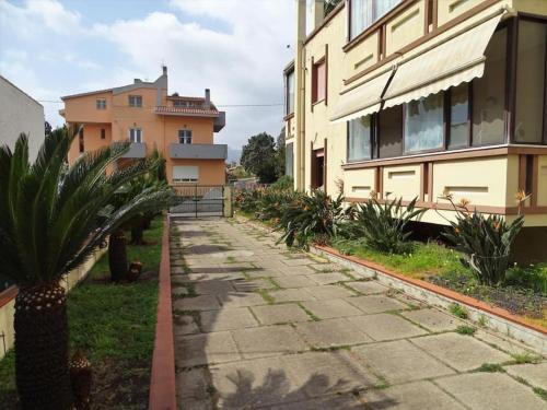 a sidewalk next to a building with a palm tree at Holiday home in La Maddalena