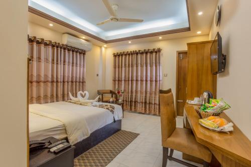 Habitación de hotel con cama, escritorio y sidx sidx de escritorio. en Memento Suites an Airport Hotel en Dhaka