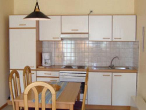 a kitchen with white cabinets and a table and chairs at Comfortable holiday home with 2 bathrooms in the Bruchttal in Bredenborn