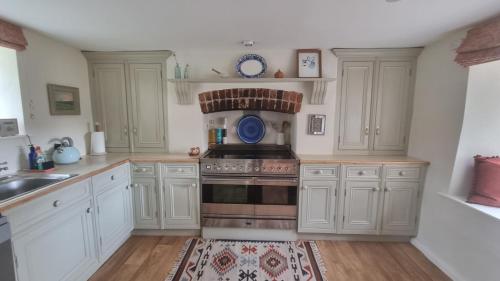 a kitchen with white cabinets and a stove top oven at Characterful Cotswold cottage in Cirencester