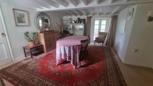 a living room with a table on a red rug at Characterful Cotswold cottage in Cirencester