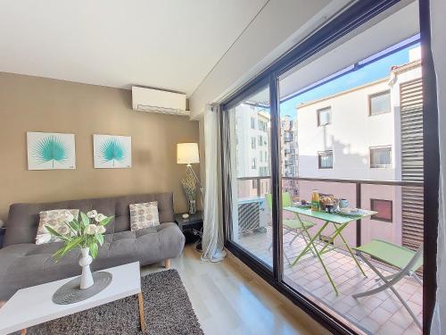 un salon avec un canapé et une grande fenêtre dans l'établissement Nestor&Jeeves - RIVOLI PALM - City center - Very close sea, à Nice