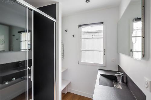 La salle de bains est pourvue d'une douche en verre et d'un lavabo. dans l'établissement Appartements Le 31bis, à Rennes