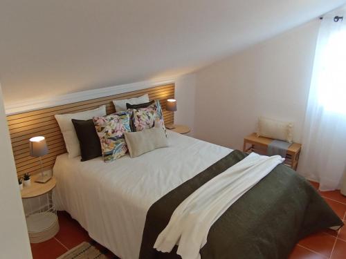 a bedroom with a large bed with many pillows at Refúgio do Seixal in Seixal