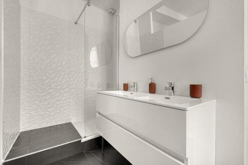 une salle de bain blanche avec un lavabo et un miroir dans l'établissement Lamazou - Appt climatisé en centre-ville, à Toulouse