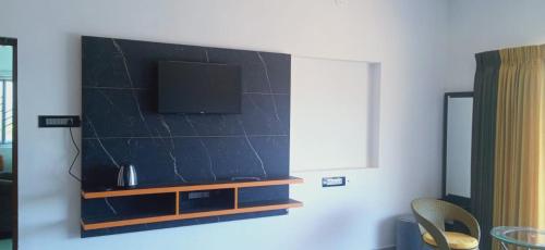 a living room with a flat screen tv on a wall at Sandy Luxury 4 Bhk Villa in Ooty