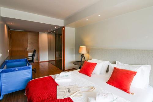 um quarto com uma grande cama branca com almofadas vermelhas em Refúgio Rio Douro em Porto