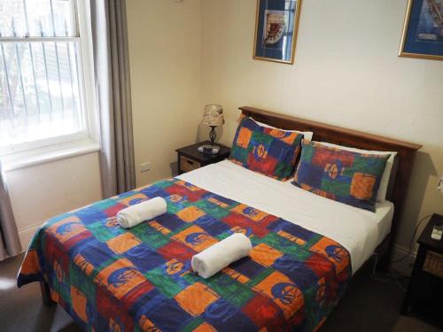 1 dormitorio con 1 cama con una manta y almohadas coloridas en Odeon Cottage - Part of Harrietts, en Unley