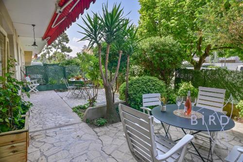 un patio con tavolo, sedie e alberi di Fully equipped beach studio a Cagnes-sur-Mer