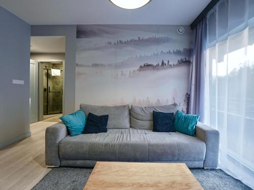 a living room with a gray couch with blue pillows at RentPlanet - Apartament Franciszkańska in Szklarska Poręba