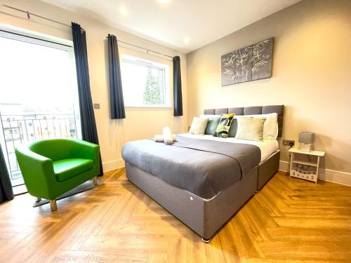 a bedroom with a bed and a green chair at Refined Living with Free Wi-Fi and Parking in Rickmansworth