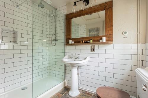 a bathroom with a sink and a mirror and a tub at Holly Lodge Boutique B&B in Thursford