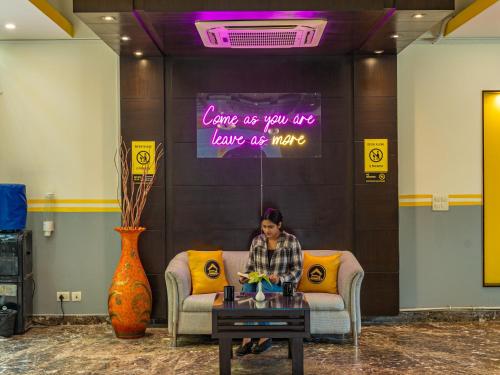 a woman sitting on a couch in a room with a table at The Hosteller Delhi in New Delhi