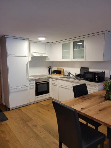 a kitchen with white cabinets and a wooden table at Waibel Appartement Bezau in Bezau