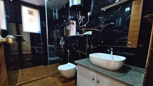 a black bathroom with a sink and a toilet at AVA Hotels and Corporates Millennium City in Gurgaon