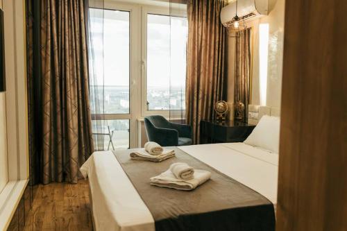 a hotel room with two towels on a bed with a window at Luxury apartment in Central Park Burgas with amazing view + private parking space in Burgas City