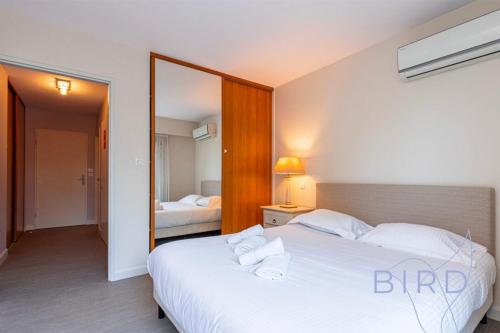 une chambre avec un grand lit blanc et un miroir dans l'établissement Spacious apartment Pool and Parking, à Antibes