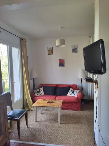 een woonkamer met een rode bank en een tv bij D&D, La maison des écureuils in Lesperon