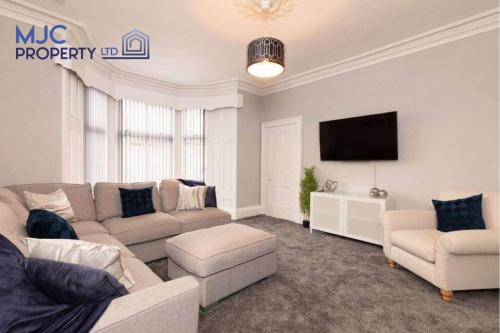 a living room with a couch and a flat screen tv at Turret Town House in Hawick
