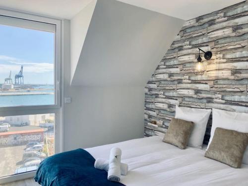 Un dormitorio con una pared de piedra y una cama grande. en Panoramic - Magnifique T3, Climatisé avec Parking, en Sète