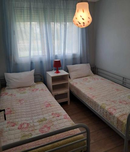 two beds in a bedroom with a lamp and a table at Olympus Miracle in Limani Litochorou